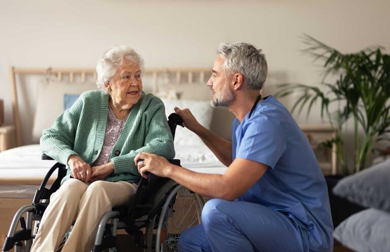 Older adults share a meal in a bright assisted living dining room beside accessible seating and clear walkways